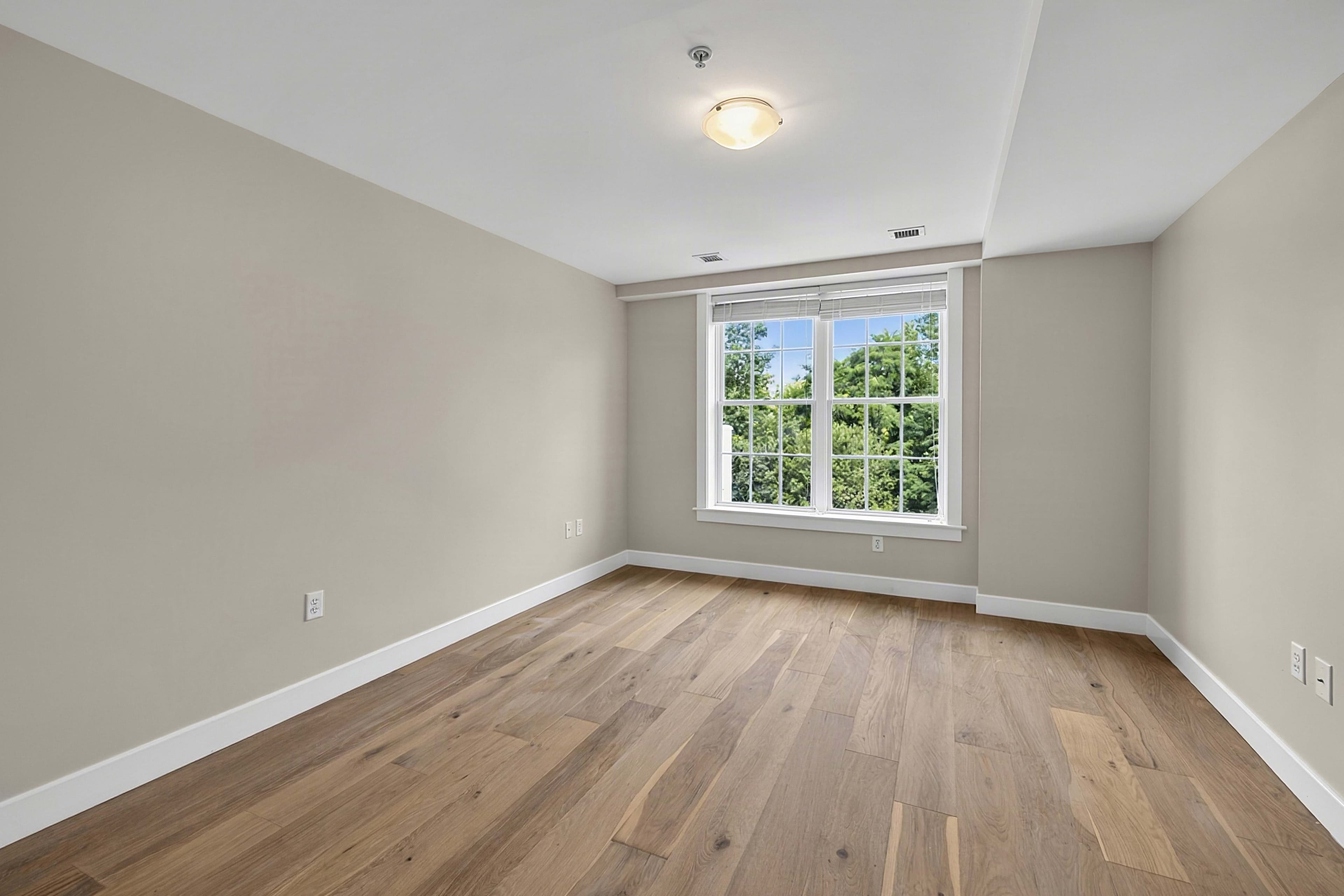 Bright bedroom with wood flooring and a large window